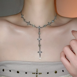 Detail of silver cross necklace with crystal Y-tassel and teardrop pendant on model