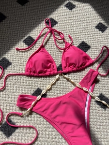 Close-up of hot pink bikini with white shell and gold bead decorative side chains