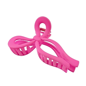 Close-up of matte pink bow-shaped hair claw clip with visible metal spring detail