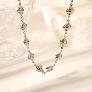 Macro view of silver conch starfish necklace with textured beads on light surface