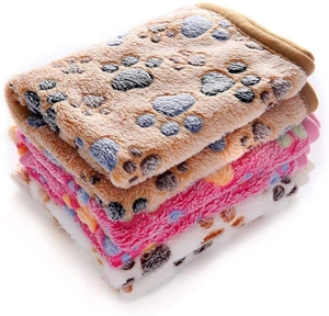 Detailed view of stacked fleece pet blankets with paw prints in brown, pink, and beige
