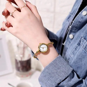 Detail of a women's gold twisted bangle watch with white dial and quartz movement