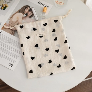 Detailed texture of cotton linen drawstring pouch with black heart prints and logo tag