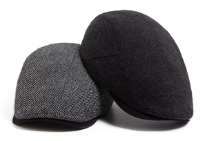 Detailed view of herringbone tweed newsboy caps in dark and light grey vintage patterns