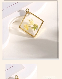 Macro detail of square gold pendant featuring real dried yellow flowers in clear resin