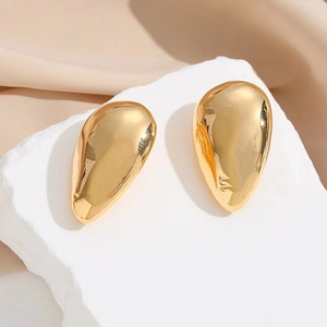 Polished 18k gold drop earrings with irregular organic shape on white stone stand