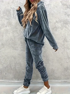 Detail of dark grey velvet lounge set featuring a hoodie and matching joggers on model