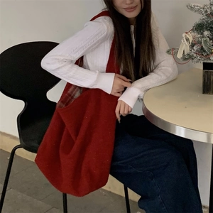Close-up of red woolen tote bag with plaid lining shown in a cozy festive setting