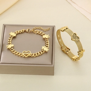 Close-up of golden MAMA and LOVE bracelets with heart charms on warm textured background