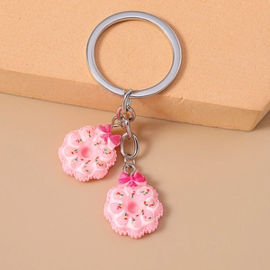 Close-up of realistic pink donut charms with bows and colorful sprinkles on a metal ring