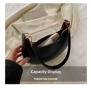 Capacity display of black crescent hobo bag with red lining and golden zipper detail