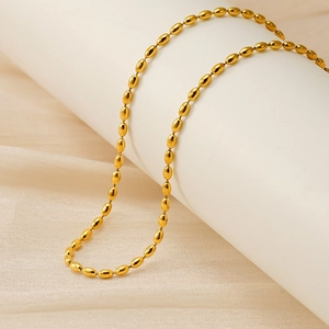 Close-up of polished 18K gold plated oval bead chain necklace on a white display stand