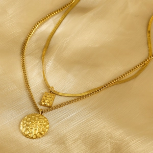 Detail view of double-layered gold necklaces with square and round hammered pendants