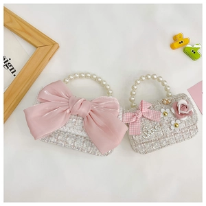 Detail of tweed kids crossbody bags with pearl handles and satin bow decorations