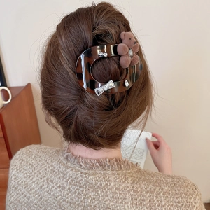 Detail of tortoise shell hair claw with plush bear and rhinestone bow on model hair