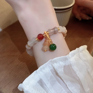 Detailed view of colorful beaded bracelet with gourd charm on model wrist with warm wood background