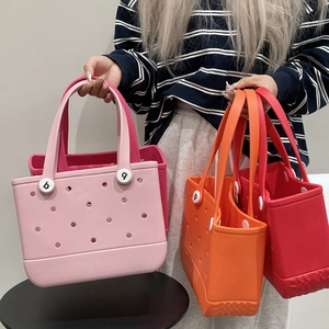 Waterproof EVA tote bags in pink, rose, orange and red held by model for beach use