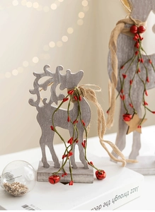 Close-up of wooden reindeer decor with red berries, burlap bow and golden bell detail