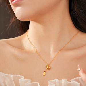 Close-up of gold-plated necklace with rocking horse and rectangular plate pendants