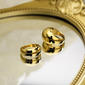 Dettaglio macro di anelli in acciaio al titanio placcati oro 18k su superficie a specchio