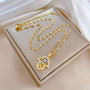 Macro shot of gold Hamsa hand pendant with blue evil eye on beige jewelry box