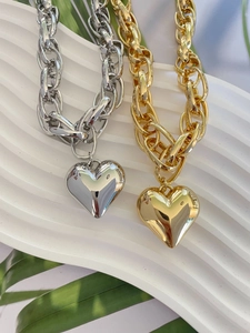 Macro shot of chunky gold and silver chain necklaces with polished heart pendants