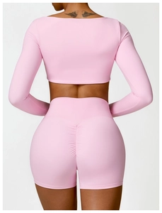 Close-up of women's pink athletic long sleeve top and scrunch butt gym shorts