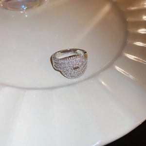 Detailed macro view of wide silver ring with pavé-set zircons on white plate