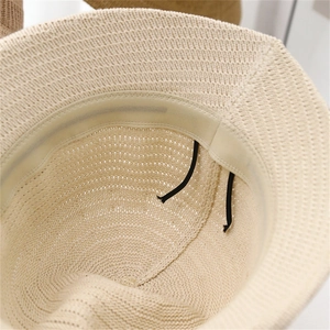Detail of beige knit bucket hat featuring adjustable inner drawstring and sweatband