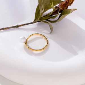 Détail d'une perle blanche sur une bague en acier titane plaqué or 18 carats