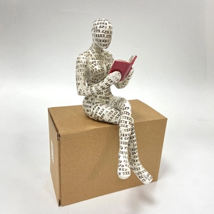 Macro detail of reading woman figurine showing textured resin surface and artistic text