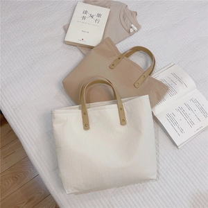 Close-up of pleated cotton tote bags with brown leather handles and rivet details