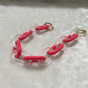 Detail of chunky acrylic chain with rose red and frosted links on white faux fur