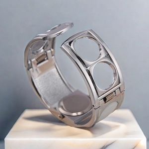 Macro shot of silver metal watch frame with circular cutouts on a marble pedestal