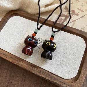 Handcrafted wooden cat pendant necklace with colorful beads and woven cord on linen tray