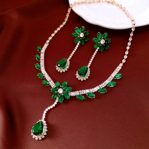Detail of vintage emerald flower pendant necklace and earrings on silk display