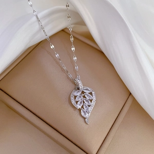 Macro detail of silver leaf pendant with micro-pave crystals in a premium gift box