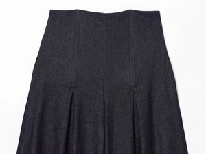 Detail of dark blue high-waisted denim skirt with visible stitching and pleated design