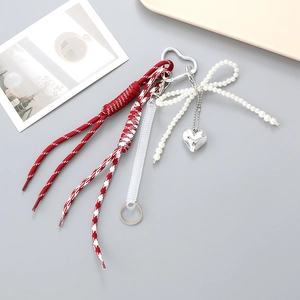 Détail d'un cordon de téléphone tressé rouge avec nœud en perles et pendentif cœur