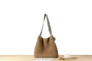 Detail of hand-woven paper straw shoulder bag with stylish black and white knotted strap