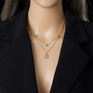 Double-layered gold sun necklace with turquoise pendant on a model wearing black suit