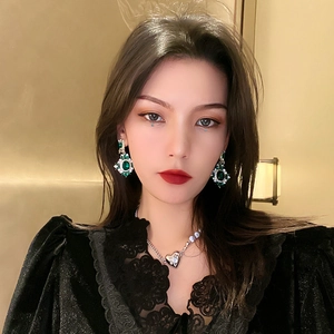Vintage emerald flower earrings and heart pendant necklace worn by a stylish model