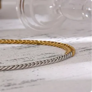 Two-tone gold and silver stainless steel twisted link chain necklace on rustic wood