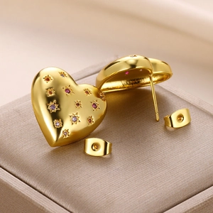 Macro detail of heart-shaped gold studs with colorful pavé cubic zirconia inlay