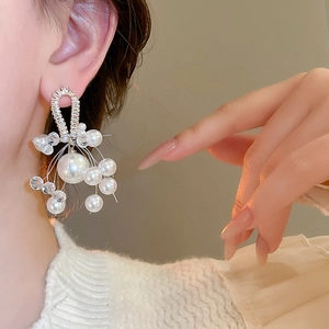 Detail of elegant cascading pearl earrings with zircon inlay worn by a model