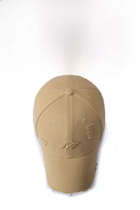 Macro detail of khaki distressed cotton baseball cap featuring gold logo embroidery