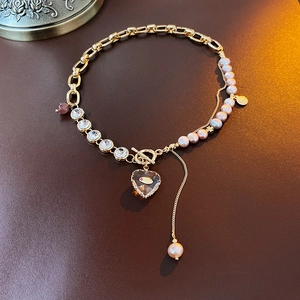 Detail of gold chain necklace with pink pearls and a heart-shaped amber crystal pendant