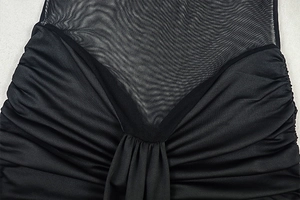 Detail of sheer black mesh V-neckline with ruching and high-quality pleated fabric