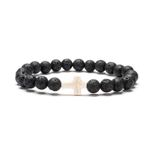Macro view of black lava rock beads and white turquoise cross charm on bracelet