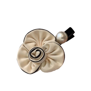 Elegant camellia hair clip with black piping and pearl detail on white background